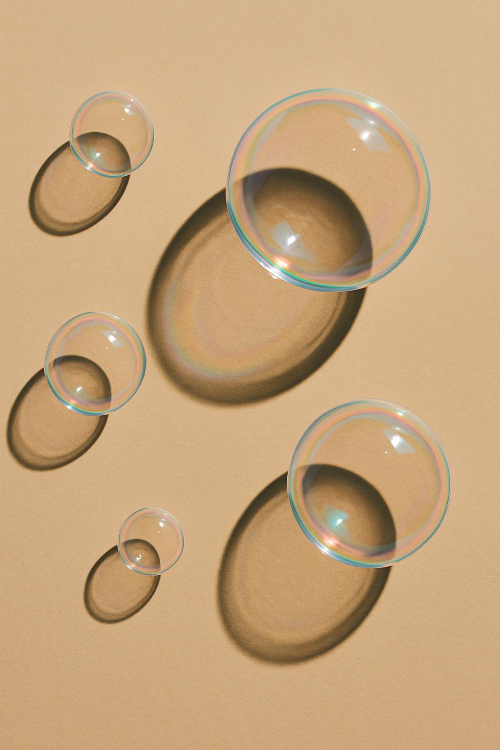 The image features clear bubbles of varying sizes, each having a distinctive rainbow-colored ring that appears illuminated...